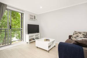 a living room with a couch and a tv at 'The Crows Nest' Spacious Studio with Balcony in Sydney