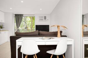 a living room with a white desk and white chairs at 'The Crows Nest' Spacious Studio with Balcony in Sydney