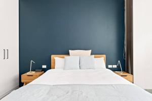 1 dormitorio con 1 cama grande y pared azul en Sunshine Pacific - A Spacious Boutique Stay en Sídney