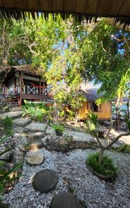 a garden with rocks and trees and a house at Nini's Beach Bungalows in Bira