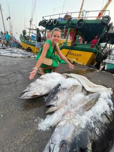 Uma mulher está ao lado de um peixe morto. em Sriyan Villa em Beruwala