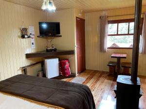 a room with a bed and a flat screen tv at Pousada Cardoso in Cambara do Sul