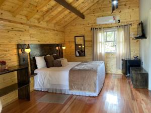 a bedroom with a bed in a wooden room at Pousada Cardoso in Cambara do Sul