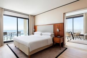 a bedroom with a bed and a balcony with a table at Riviera Marriott Hotel La Porte De Monaco in Cap d'Ail