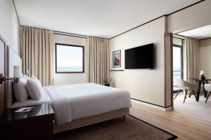 a hotel room with a bed and a dining room at Riviera Marriott Hotel La Porte De Monaco in Cap d'Ail