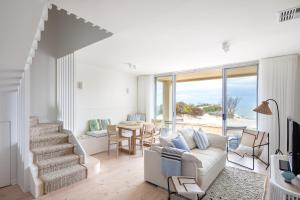 Port AdelaidePearl, Designer Beachfront Retreat, Semaphore Park的带白色沙发和楼梯的客厅