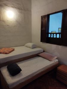 2 Betten in einem Zimmer mit Fenster in der Unterkunft Casa Hostal Colonial VaraEchada in Barichara