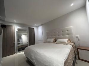 HERMOSO!! MODERNO, UBICACION EXCLUSIVA!! 2 ALCOBAS في بارانكويلا: غرفة نوم بيضاء بسرير كبير وتلفزيون