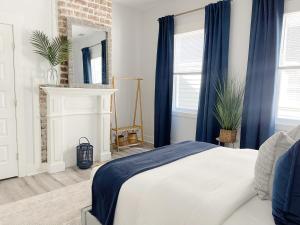 a bedroom with a bed with blue curtains and a fireplace at New! Stylish 1900s Renovated Duplex Apartment Building Near Forsyth & River St in Savannah