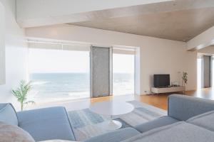 a living room with a table and a view of the ocean at 湘南OCEAN HOUSE in Koshigoe