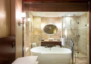 uma casa de banho com uma banheira, um lavatório e um espelho. em Beijing Marriott Hotel Northeast em Pequim