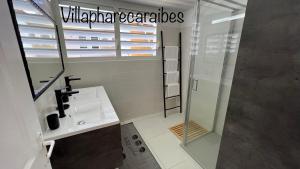 a bathroom with a sink and a glass shower at VILLA PHARE CARAÏBES Guadeloupe in Le Moule