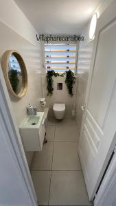 a bathroom with a toilet and a sink and a mirror at VILLA PHARE CARAÏBES Guadeloupe in Le Moule