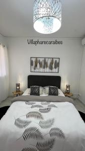 ein Schlafzimmer mit einem Bett mit einer schwarzen und weißen Decke in der Unterkunft VILLA PHARE CARAÏBES Guadeloupe in Le Moule