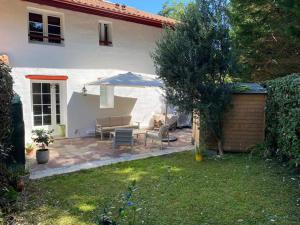 a patio with a couch and an umbrella in a yard at Les chambre de amour in Urrugne