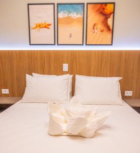 a bedroom with a white bed with four pictures on the wall at Ubatuba Eco Hotel in Ubatuba