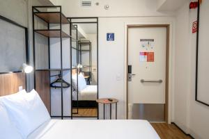 ein Schlafzimmer mit einem Bett und ein Zimmer mit einem Spiegel in der Unterkunft ibis Guarapuava in Guarapuava