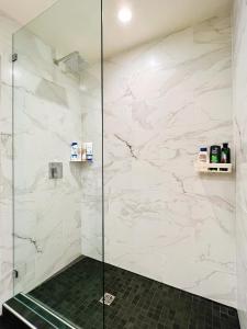 y baño con ducha y paredes de mármol blanco. en Waterfront Room1 with Private Bath near Marina, en Gibsons