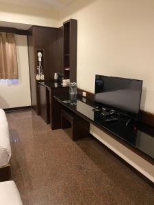 Habitación de hotel con escritorio y TV de pantalla plana. en YUAI FU HAO Hotel, en Taichung
