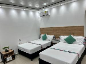 Duas camas num quarto com paredes brancas em HOTEL TORRE DELUXE ¨SANTORINI¨ em Doradal