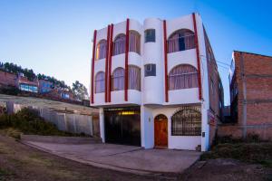 un edificio blanco y rojo con una puerta en Hostal Mirador Korichaska en Puno