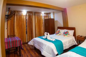 1 dormitorio con 2 camas y toallas. en Hostal Mirador Korichaska en Puno