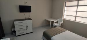 Dormitorio con cama, escritorio y TV en Hostal Center en Santa Cruz de la Sierra