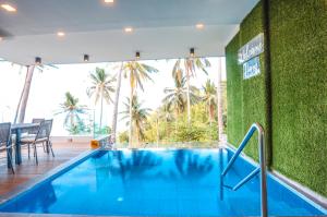 a swimming pool in a hotel with a green wall at Noni's Resort in Alitagtag