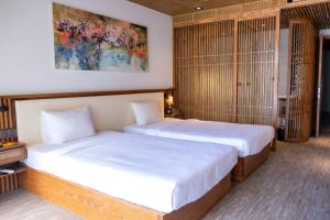duas camas num quarto com lençóis brancos em LUK Inn Hotel em Da Nang