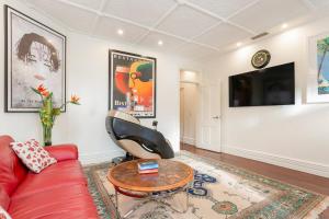 a living room with a red couch and a table at 'Lady Beatle' Quirky Character Terrace near Harbour in Sydney