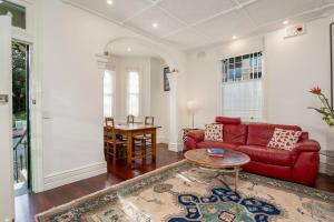 uma sala de estar com um sofá vermelho e uma mesa em 'Lady Beatle' Quirky Character Terrace near Harbour em Sydney