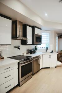 una cocina con electrodomésticos de acero inoxidable y armarios blancos en Toronto Junction Hideaway, en Toronto
