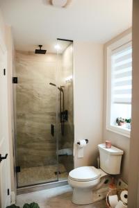 La salle de bains est pourvue de toilettes et d'une douche en verre. dans l'établissement Toronto Junction Hideaway, à Toronto