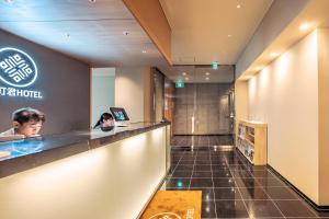 una hall di un hotel con due persone sedute al bancone di 谷町君Hotel 難波77 ad Osaka