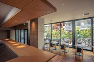 a restaurant with tables and chairs and large windows at 谷町君Hotel 難波77 in Osaka