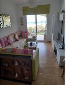 een woonkamer met een bank en een tv bij Appartement Al cudia smir in Fnidek