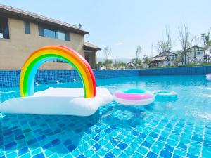 a pool with a rainbow and two inflatables in the water at Yuncheng Yunxi Furusato-Banma Resort in Yuncheng