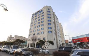 Un grand bâtiment avec des voitures garées dans un parking dans l'établissement Hotel Grand Bay Boryeong, à Boryeong