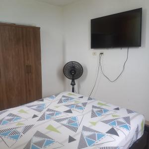 a bed with a comforter with a television on a wall at Apartamento entero Valledupar in Valledupar