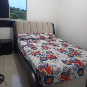 a bed with a colorful comforter in a room at Apartamento entero Valledupar in Valledupar