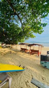 Una playa con mesas de picnic y una tabla de surf en la arena. en Villa 215, en Weligama 9 fotos más