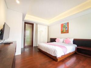 a bedroom with a bed and a flat screen tv at Dzawani Villa Ungasan in Uluwatu