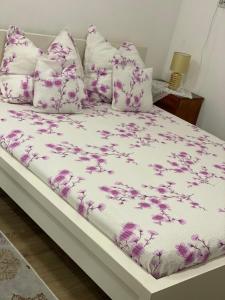 un letto con lenzuola e cuscini viola e bianchi di Ardelean Apartment a Oradea