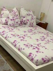 a bed with purple and white sheets and pillows at Ardelean Apartment in Oradea