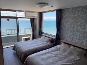 two beds in a room with a view of the ocean at Support Inn Minami-Chita Annex Hamachaya in Minamichita