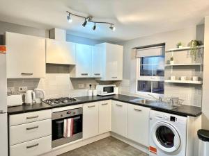 a kitchen with white cabinets and a washer and dryer at Balne Mill Grove in Wakefield
