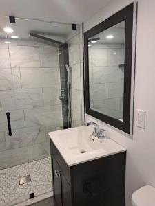 a bathroom with a sink and a shower with a mirror at Suite ravissante MYD in Milton