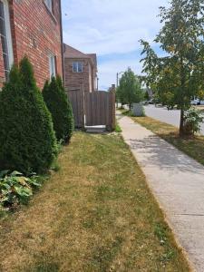 a sidewalk next to a brick house with a fence at Suite ravissante MYD in Milton