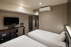 a hotel room with two beds and a desk and a tv at the b namba-kuromon in Osaka