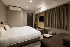 a hotel room with a white bed and a couch at the b namba-kuromon in Osaka
